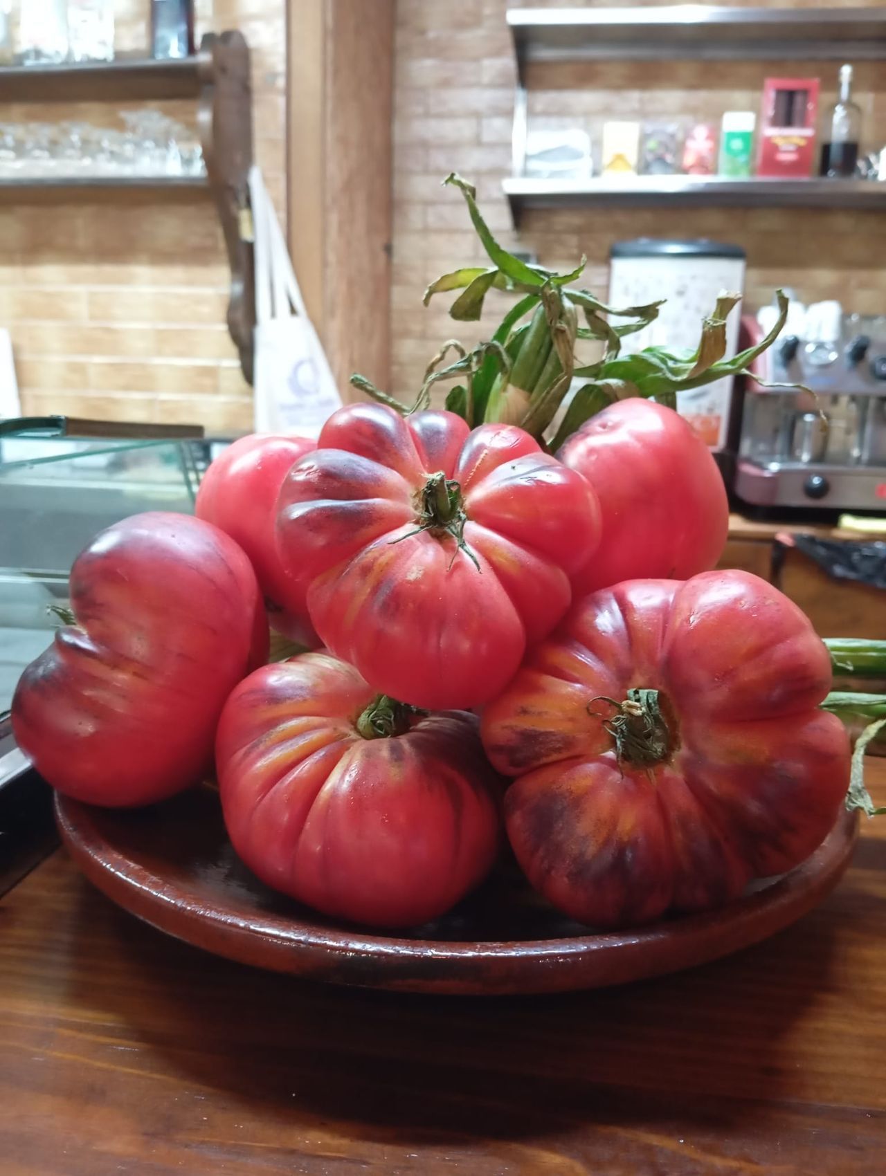 A clay plate piled with ripe heirloom tomatoes from the garden, on El Molino's bar